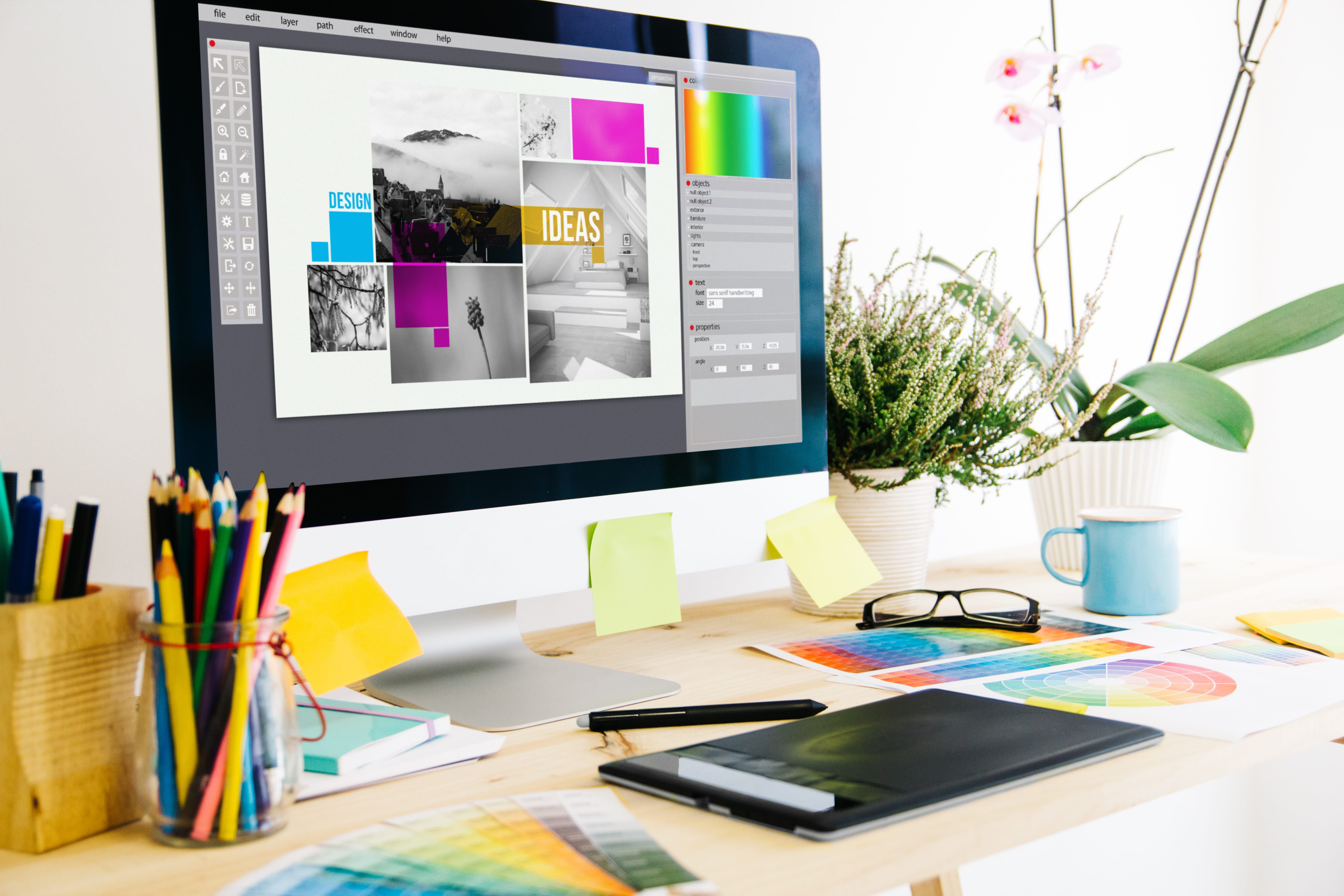 Pre-press design station with monitor showing layout and color reference materials